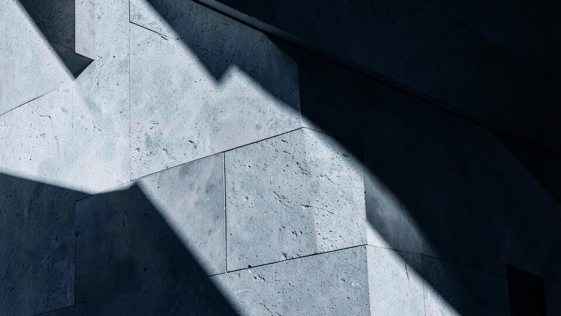 Architectural stone facade with strong diagonal light and shadow